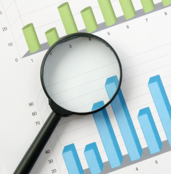 Magnifying glass over green and blue charts.